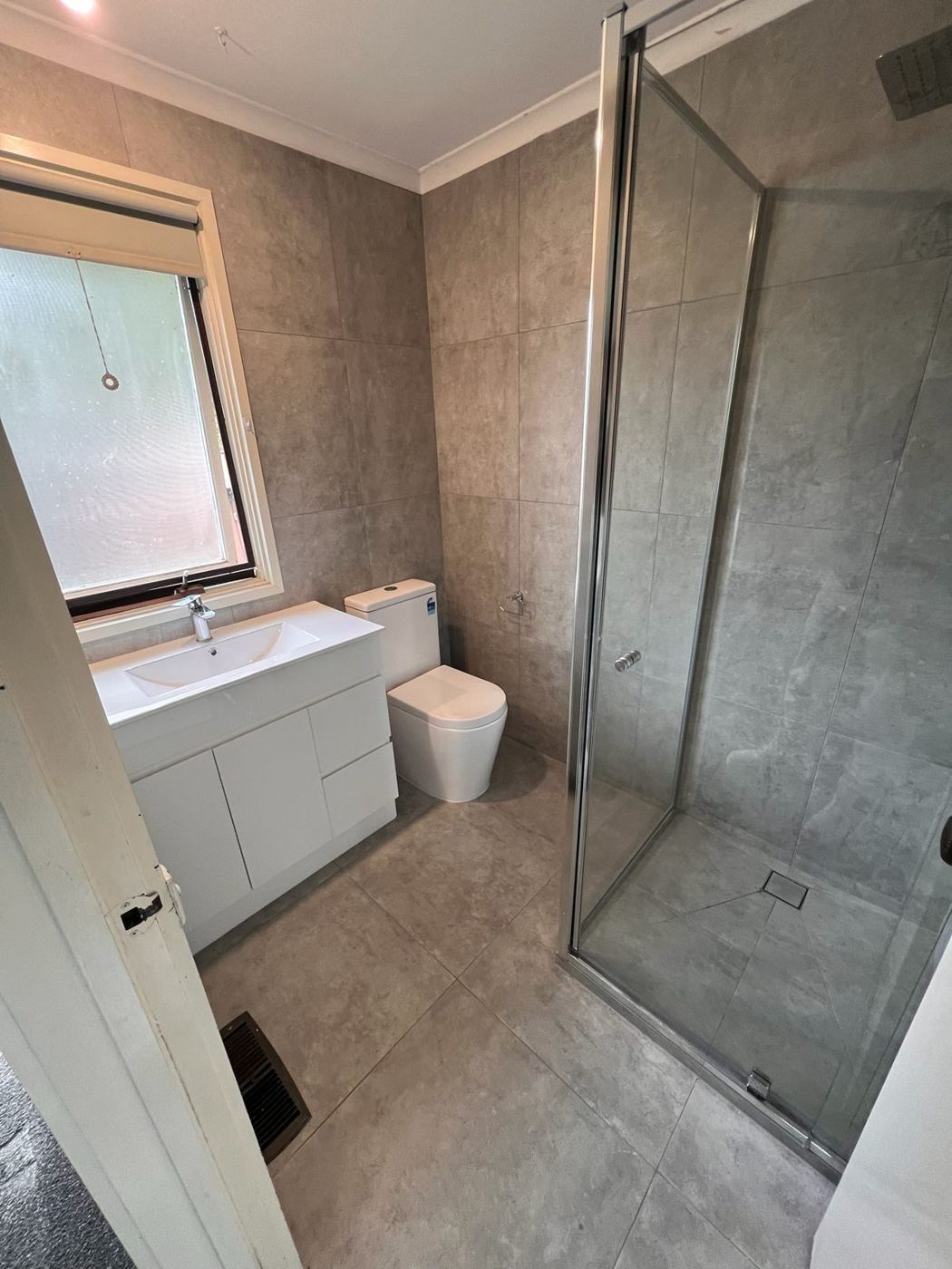 Same bathroom after renovation, with new vanity and shower screen