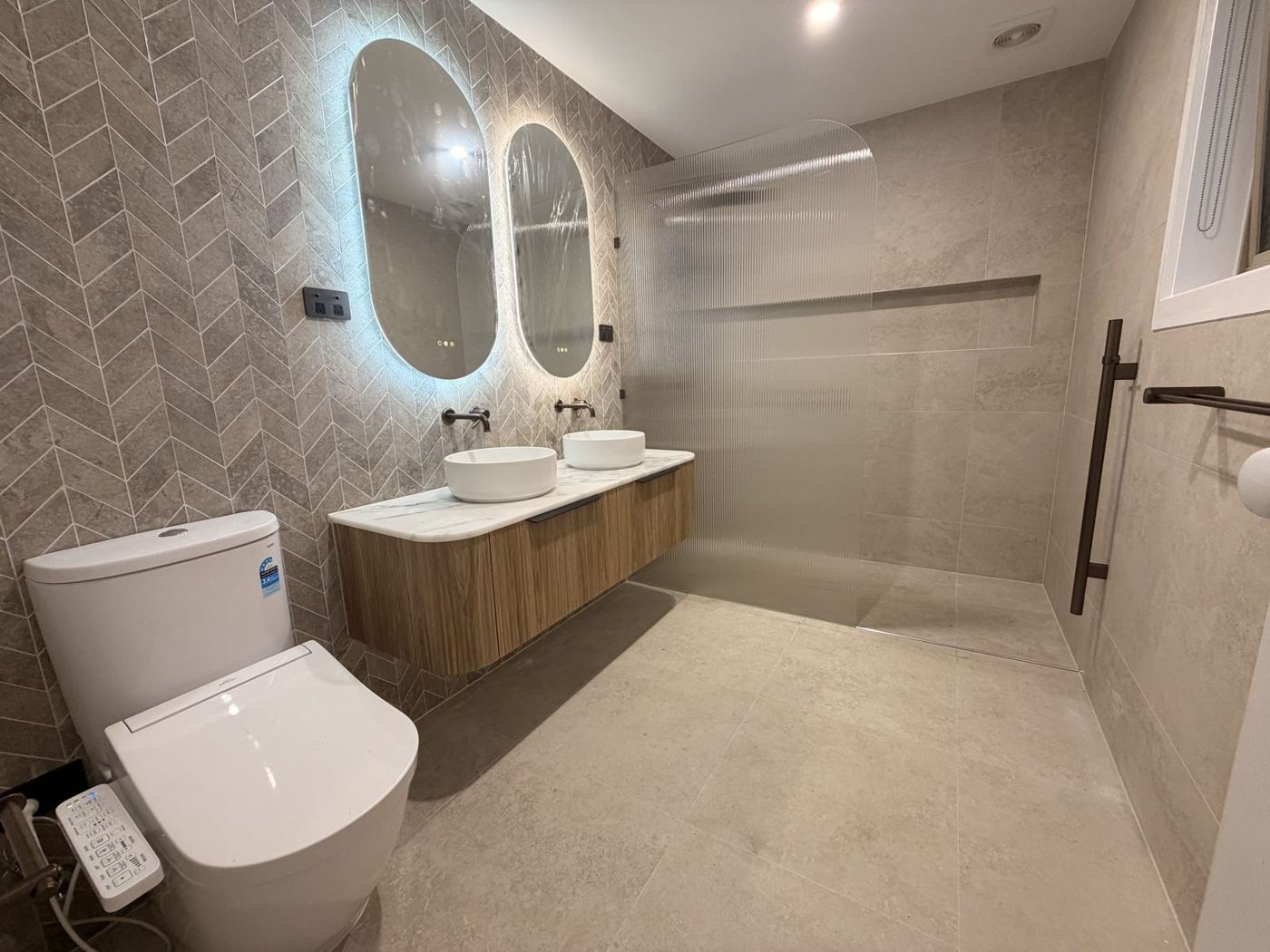 Renovated bathroom with backlit mirrors and walk-in shower