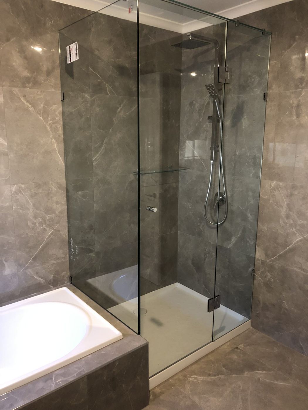 Frameless shower screen beside a bath
